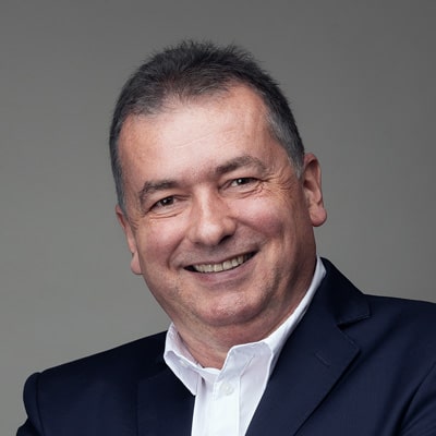 zdjęcie portretowe mężczyzny z szerokim uśmiechem, owalną twarzą i krótkimi czarnymi włosami