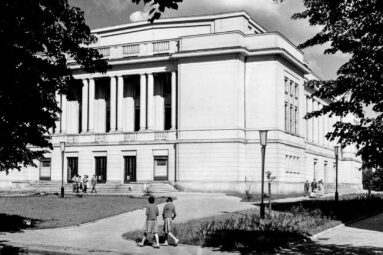 Spacerujący ludzie przed budynkiem filharmonii