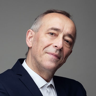 zdjęcie portretowe mężczyzny z przechyloną na bok głową, z siwymi włosami i zakolami