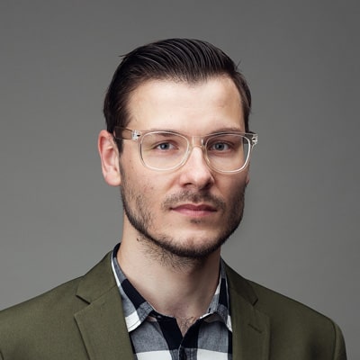zdjęcie portretowe młodego, przystojnego mężczyzny w okrągłych okularach z przezroczystymi oprawkami, z włosami zaczesanymi do tyłu