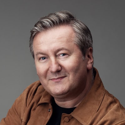 zdjęcie portretowe mężczyzny z ułożonymi na bok włosami, z owalną twarzą i podłużnym nosem