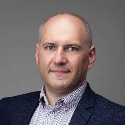 zdjęcie portretowe mężczyzny z głową do połowy łysą i krótkimi siwymi włosami po bokach