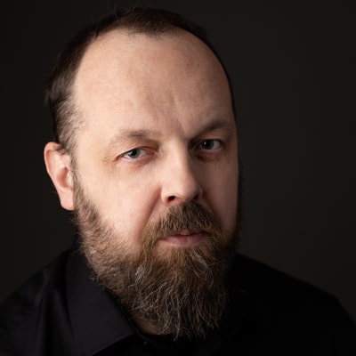 Grzegorz Korybalski zdjęcie portretowe mężczyzny w średnim wieku z ciemną brodą