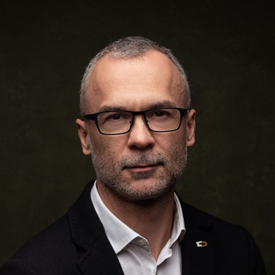 Wojciech Kondarewicz zdjęcie portretowe krótko obstrzyżonego mężczyzny w okularach, w jasnej koszuli i ciemnej marynarce