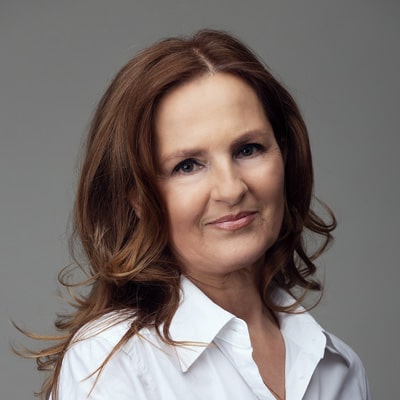 zdjęcie portretowe usmiechniętej kobiety z długimi, brązowymi włosami, w białej bluzce