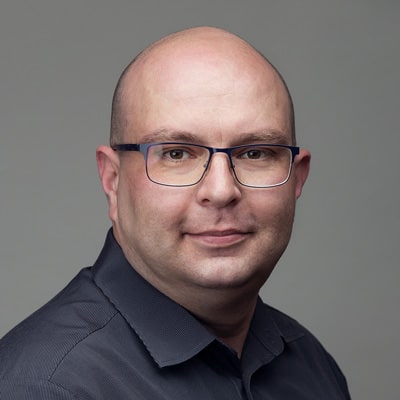 zdjęcie portretowe łysiejącego mężczyzny w okularach, w czarnej koszuli