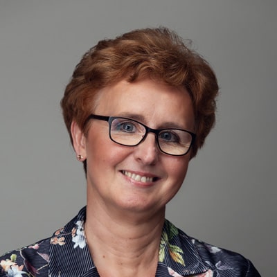 zdjęcie portretowe uśmiechniętej kobiety w średnim wieku w okularach, z krótkimi włosami