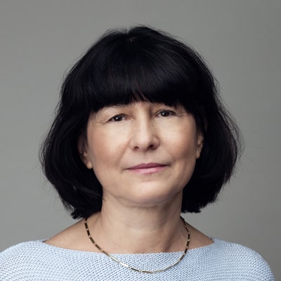 zdjęcie portretowe kobiety w średnim wieku, w białej bluzce, z czarnymi włosami średniej długości