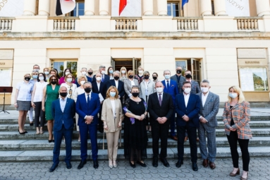 Grupa ludzi pozuje do zdjęcia na tle gmachu filharmonii