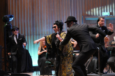 dwoje mężczyzn i kobieta w okularach przeciwsłonecznych wykonują bluesa tańcząc i śpiewając