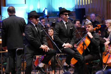 Zbigniew Zamachowki i Maciej Miecznikowski jako Bracia Blues w garniturach, kapeluszach i okularach przeciwsłonecznych na estradzie Fp