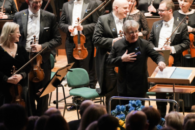 zdjęcie muzyków stojących na estradzie podczas oklasków oraz na estradzie i dyrygenta dziękującego publiczności