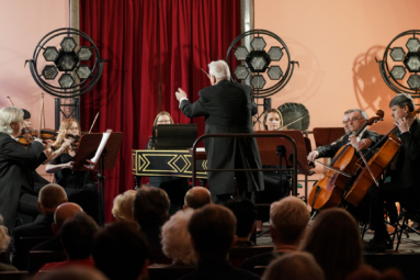 zdjęcie dyrygenta i orkiestry kameralnej na estradzie w trakcie koncertu