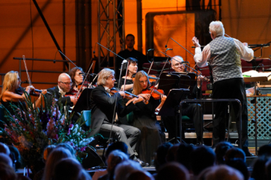 dyrygent i muzycy orkiestry na estradzie podczas koncertu plenerowego