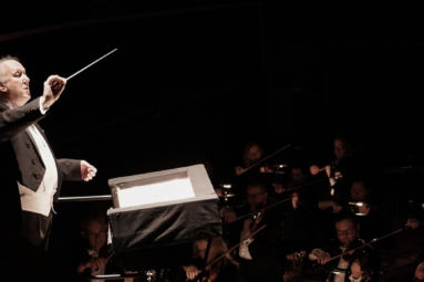 zdjęcie dyrygenta kierującego orkiestrą i chórem