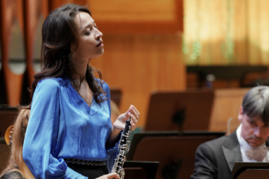 zdjęcie oboistki w satynowej, niebieskiej bluzce, trzymającej w rękach obój