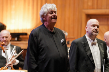 dyrygent na estradzie, odwrócony i uśmiechający się do publiczności