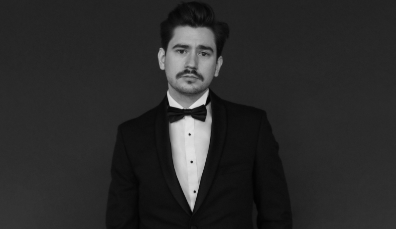 biało-czarne zdjęcie młodego mężczyzny z wąsem w smokingu