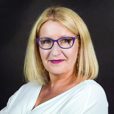 Kobieta w średnim wieku we fioletowych okularach uśmiecha się