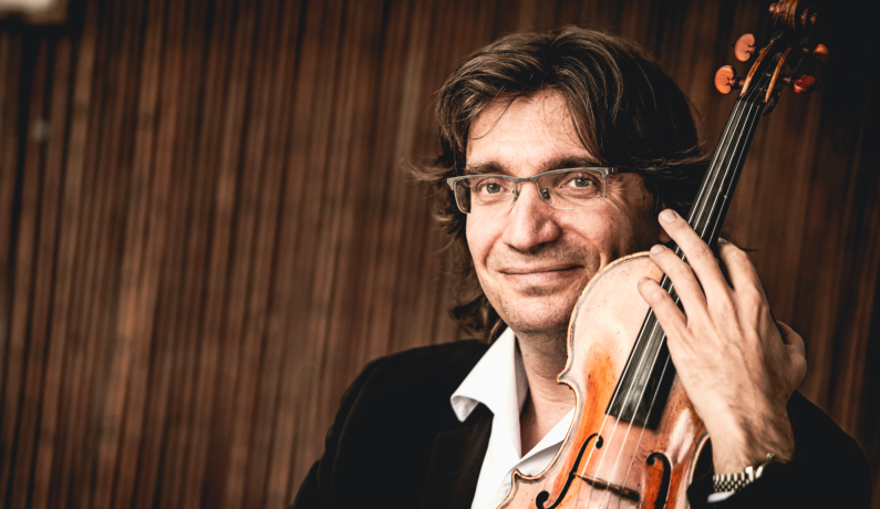 zdjęcie mężczyzny w okularach pozującego ze skrzypcami w ręku