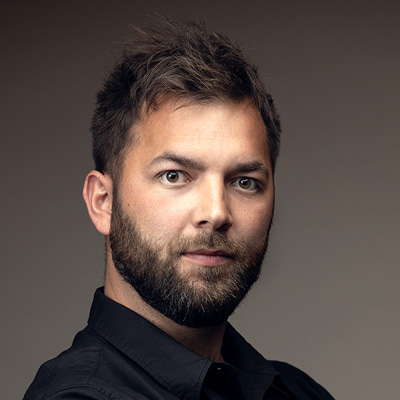 Michał Tyszka zdjęcie portretowe młodego mężczyzny, z czarnymi włosami i ciemnym zarostem