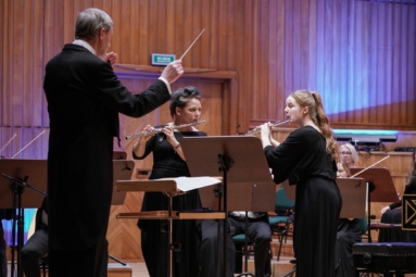 dwie kobiety grają na fletach, dyrygent stoi tyłem