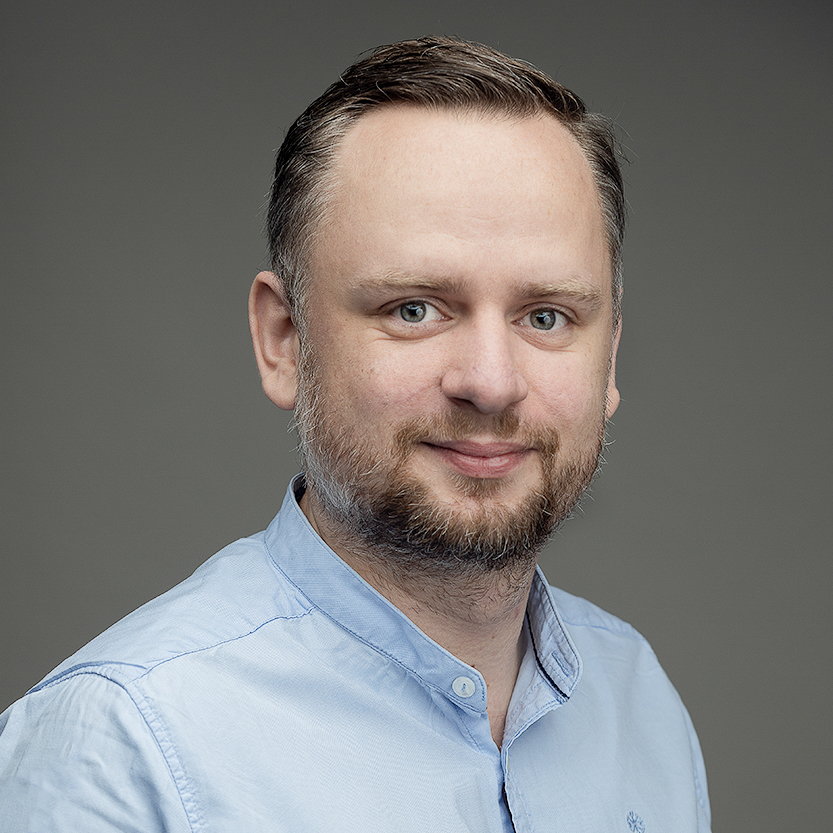 zdjęcie portretowe młodego mężczyzny z zaczesanymi do tyłu włosami, zarostem, wysokim czołem