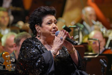 zdjęcie kobiety w czarnych krótkich włosach, w czarnej, cekinowej sukience śpiewającej do mikrofonu