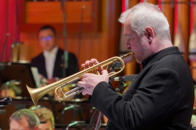 zdjęcie mężczyzny w siwych włosach grającego na trabce