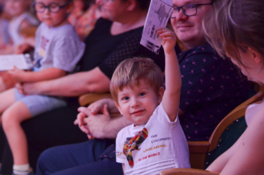 zdjęcie chłopca siedzącego na widowni, trzymającego w ręku bilet na kocnert