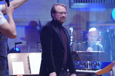 zdjęcie młodego mężczyzny w okularach uśmiechającego się do publiczności