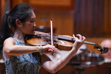 zdjęcie młodej kobiety o azjatyckiej urodzie, z włosami upiętymi w kuca, grającej na altówce