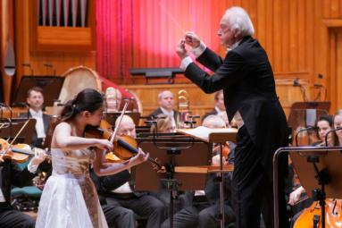 zdjęcie starszego, siwego dyrygenta i młodej skrzypaczki podczas grania koncertu