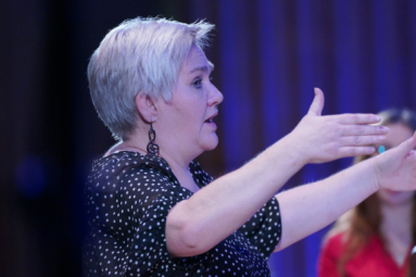 zdjęcie dyrygentki w jasnych włosach z uniesionymi rękami