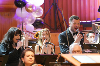 zdjęcie trójki wokalistów śpiewających z radością do mikrofonów