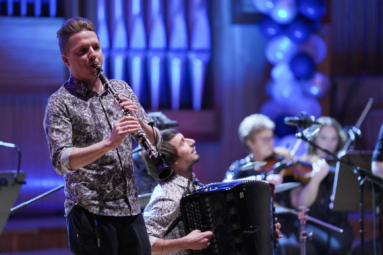 młody mężczyzna we wzorzystej koszuli grający na klarnecie