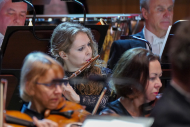 zdjęcie młodej dziewczyny w kręconych włosach grającej na flecie poprzecznym