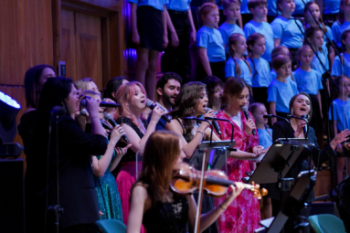 zdjęcie wokalistów śpiewających do mikrofonów