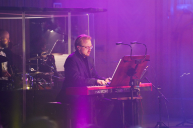 zdjęcie pianisty podczas koncertu rozrywkowego, oświetlonego różowo-fioletowymi światłami