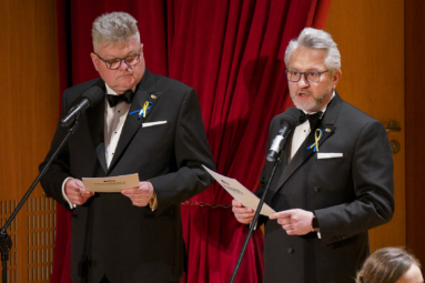 zdjęcie dwóch mężczyzn w eleganckich smokingach przemawiających do publiczności