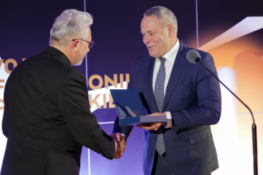 Zdjęcie mężczyzny w garniturze wręczającego nagrodę drugiemu mężczyźnie w garniturze