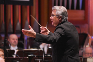 zdjecie dyrygenta z unieisonymi rekami podczas koncertu