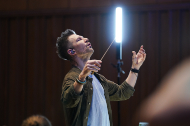zdjęcie dyrygenta unoszącego ku górze ręce i głowę