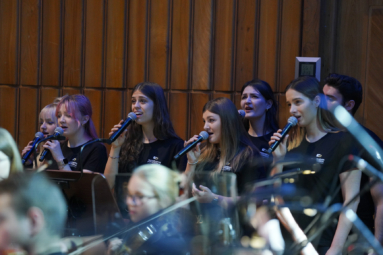 zdjęcie wokalistów Orchestry4Young ubranych w czarne koszulki z logo FP, śpiewających do mikrofonów