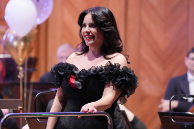 zdjęcie śpiewaczki w sukience z odkrytymi ramionami uśmiechajacej się szeroko