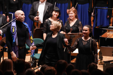 zdjęcie dwóch kobiet i mężczyzny zwróconych w stronę oklaskującej ich publiczności