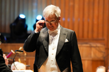 Zdjęcie siwego mężczyzny we fraku spoglądającego zza okularów