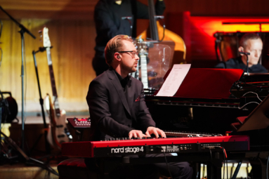 Zdjęcie młodego mężczyzny w okularach grającego na czerwonym pianinie cyfrowym