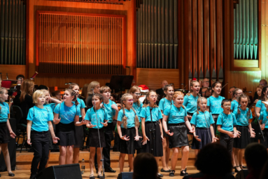 zdjęcie dzieci w niebeskich koszulkach śpiewających na estradzie FP