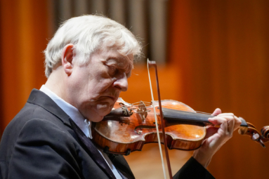 siwy, starszy mężczyzna grający na skrzypcach z zamkniętymi oczami